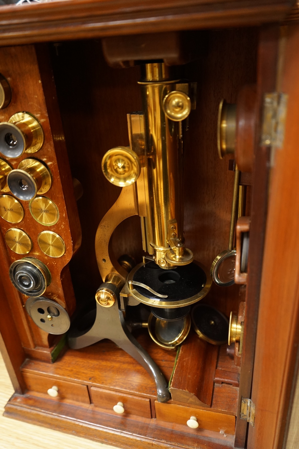 A Victorian binocular brass microscope, unsigned, in a fitted, glass fronted case with a good selection of alternative lenses and accessories, all in fitted compartments, plus three integral drawers to hold microscope sl